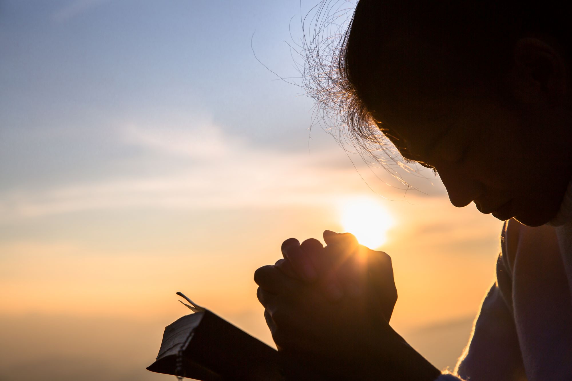 Jeune femme priant dehors avec la bible sur ses genoux