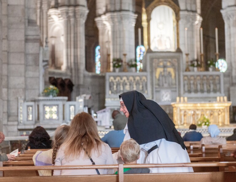 Soeur bénédictine parlant à des pèlerins dans la Basilique